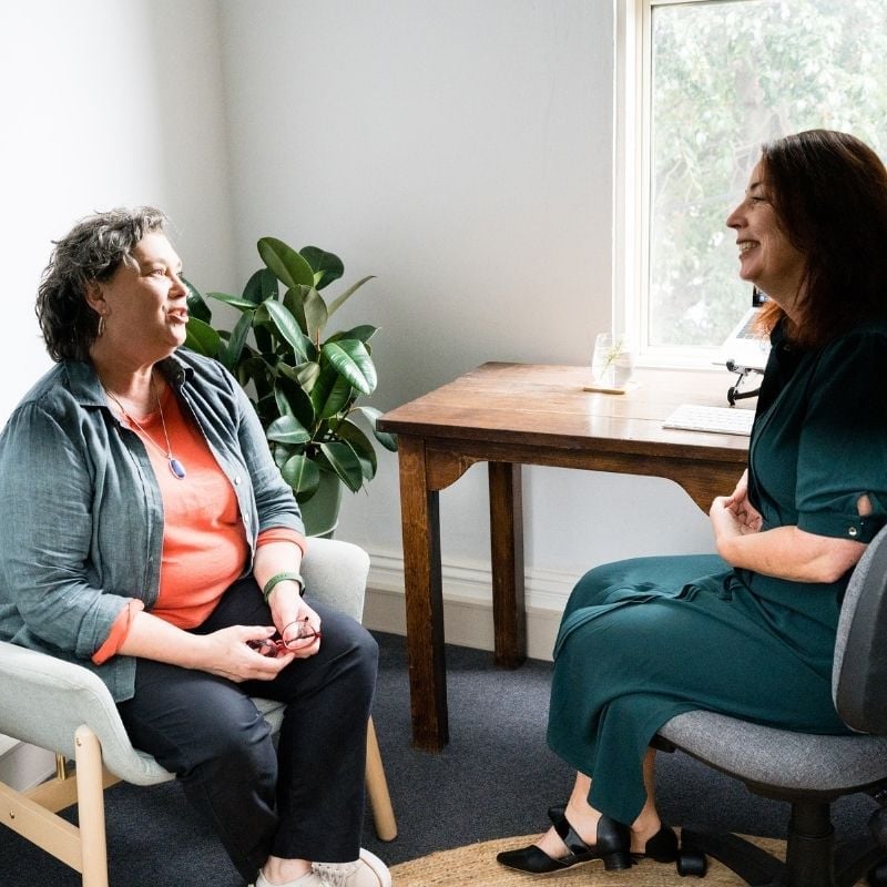 1-hour-initial-appointment female practitioner sitting in clinic with patient pointing to results on printed report