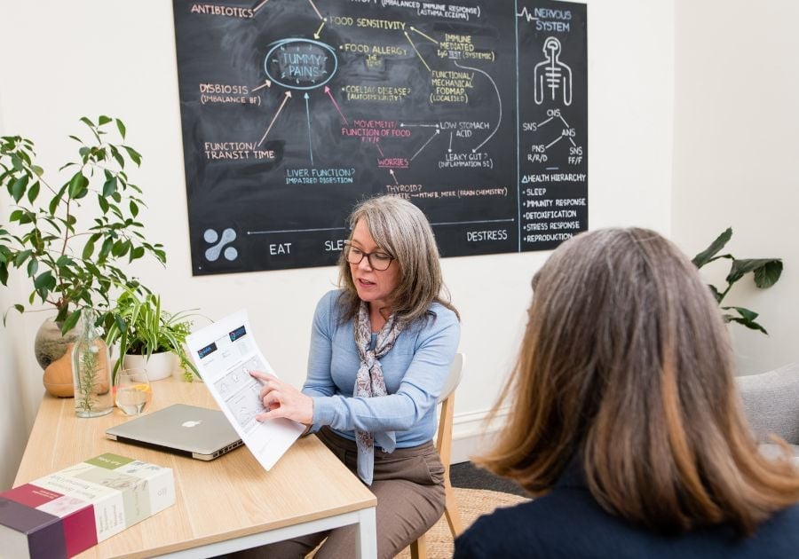 services-bee-jabe-discussing-with-folder-popular female practitioner sitting in clinic with patient pointing to results on printed report