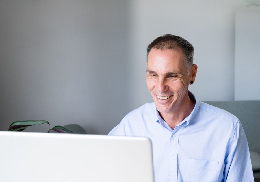 services-liv-bee-having-tea male practitioner sitting in clinic looking at laptop smiling